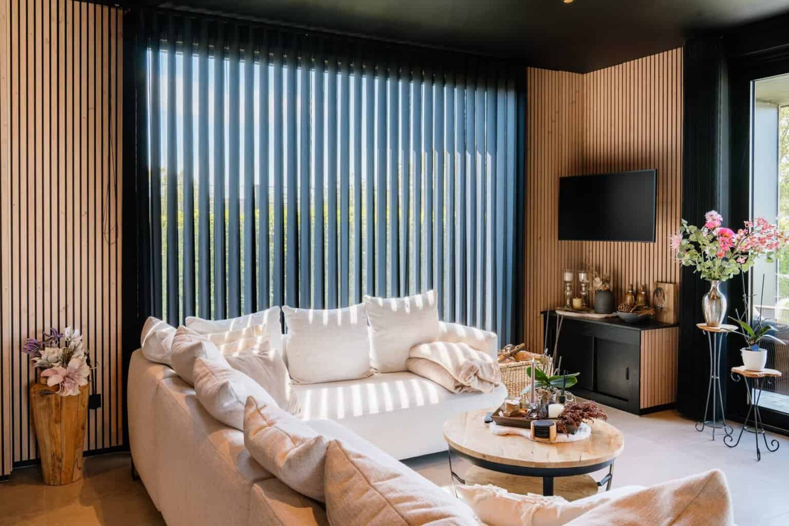 Zwarte Illusions verticale lamellen in living met houten wandpanelen en crème zetel — Balen