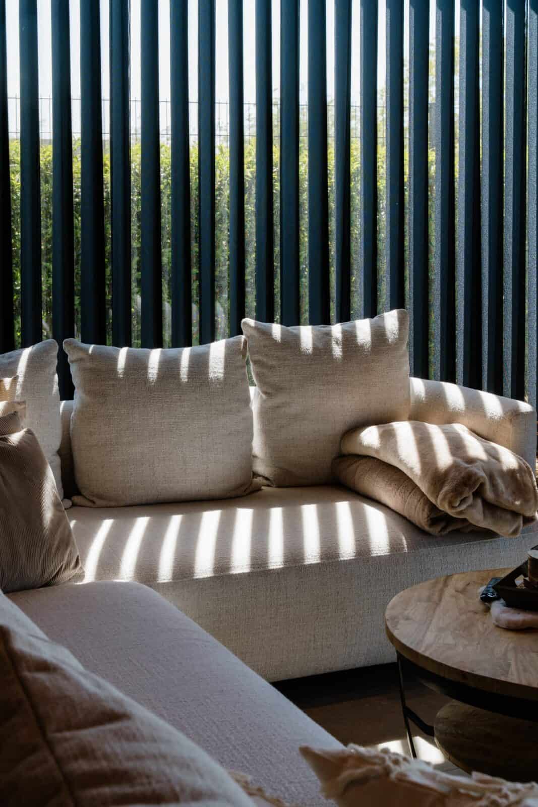 Detail lichtspel door zwarte Illusions lamellen op crème zetel — woning Balen