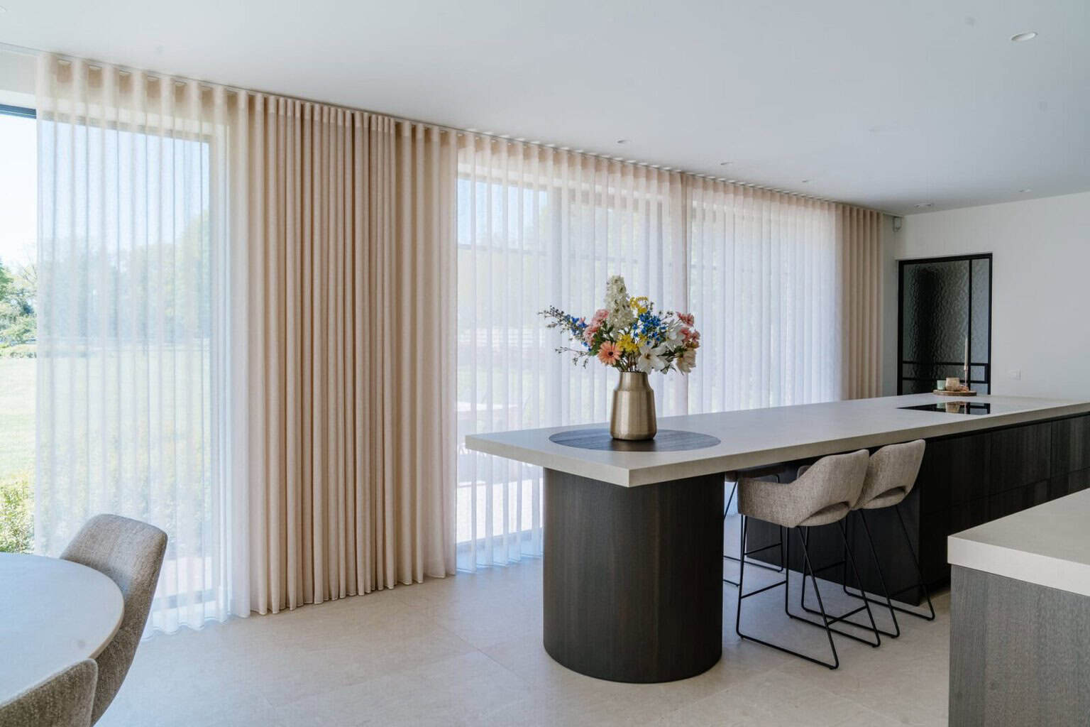 Kookeiland met donker hout en zandbeige wave gordijnen op achtergrond - keuken woning Balen
