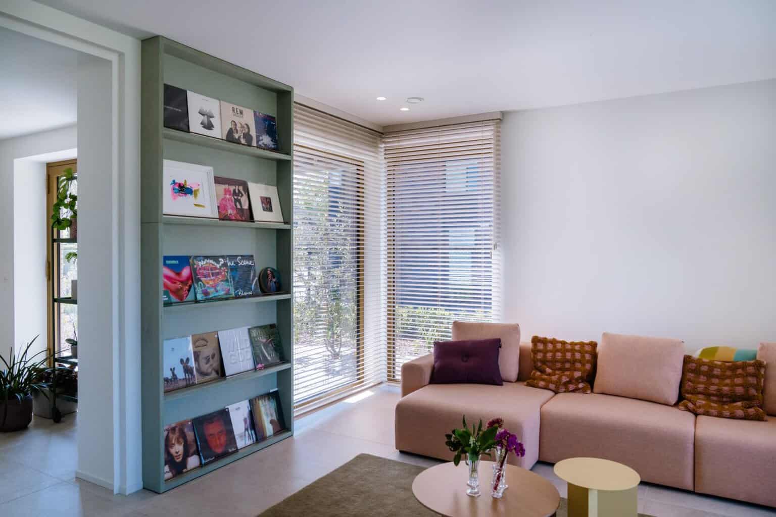 Houten lamellen in hoekraam naast vinylrek en roze hoekzetel — living Willekens Lommel