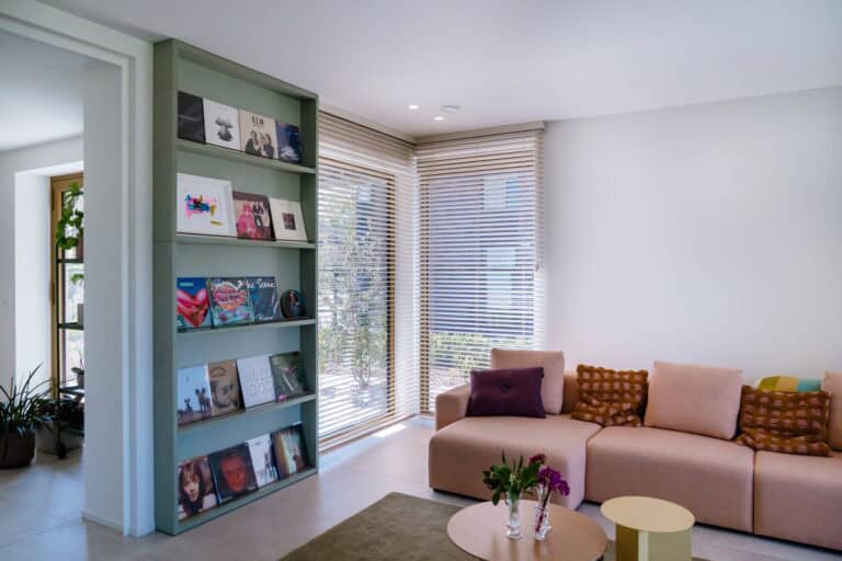Houten lamellen in hoekraam naast vinylrek en roze hoekzetel — living Willekens Lommel