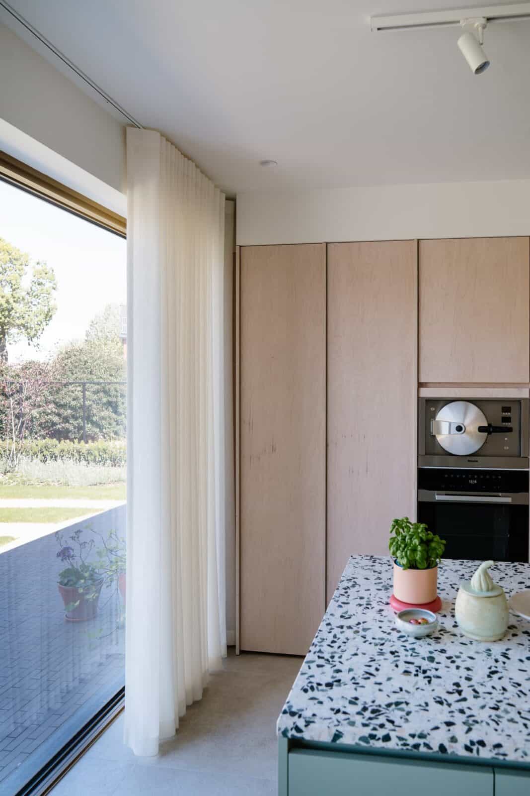 Wave gordijn naast raam in moderne keuken met terrazzo werkblad — woning Lommel