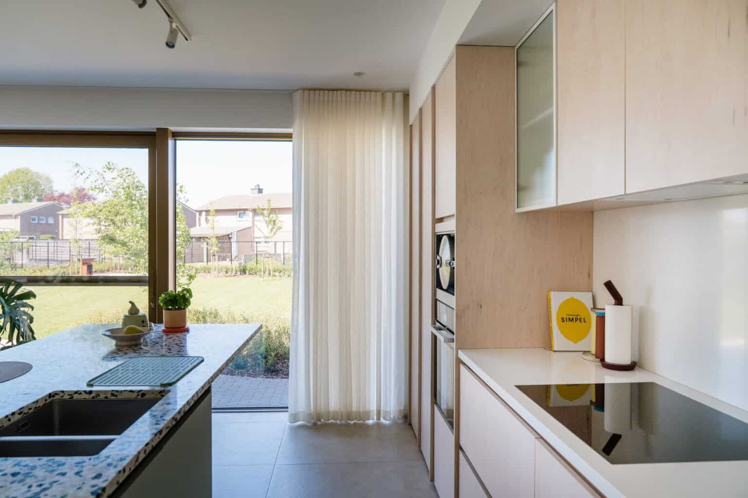 Transparant wave gordijn in keuken met houten kasten en tuinzicht — Lommel