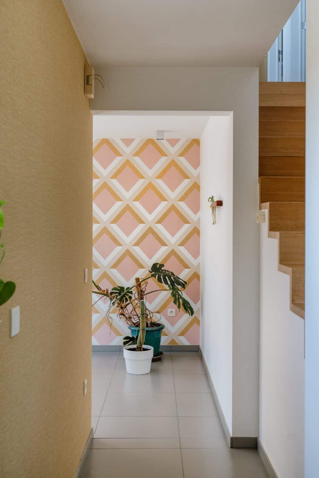 Geometrisch ruitpatroon behang in roze en okergeel in traphal — woning Mol