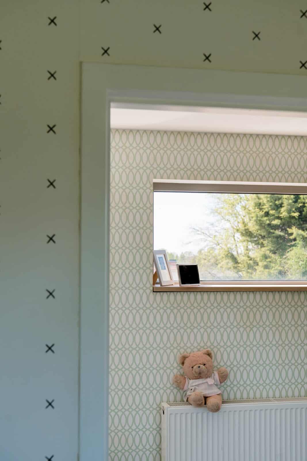 Detail kinderkamer behang met kruis-patroon en groen ovaalpatroon naast raam — woning Mol