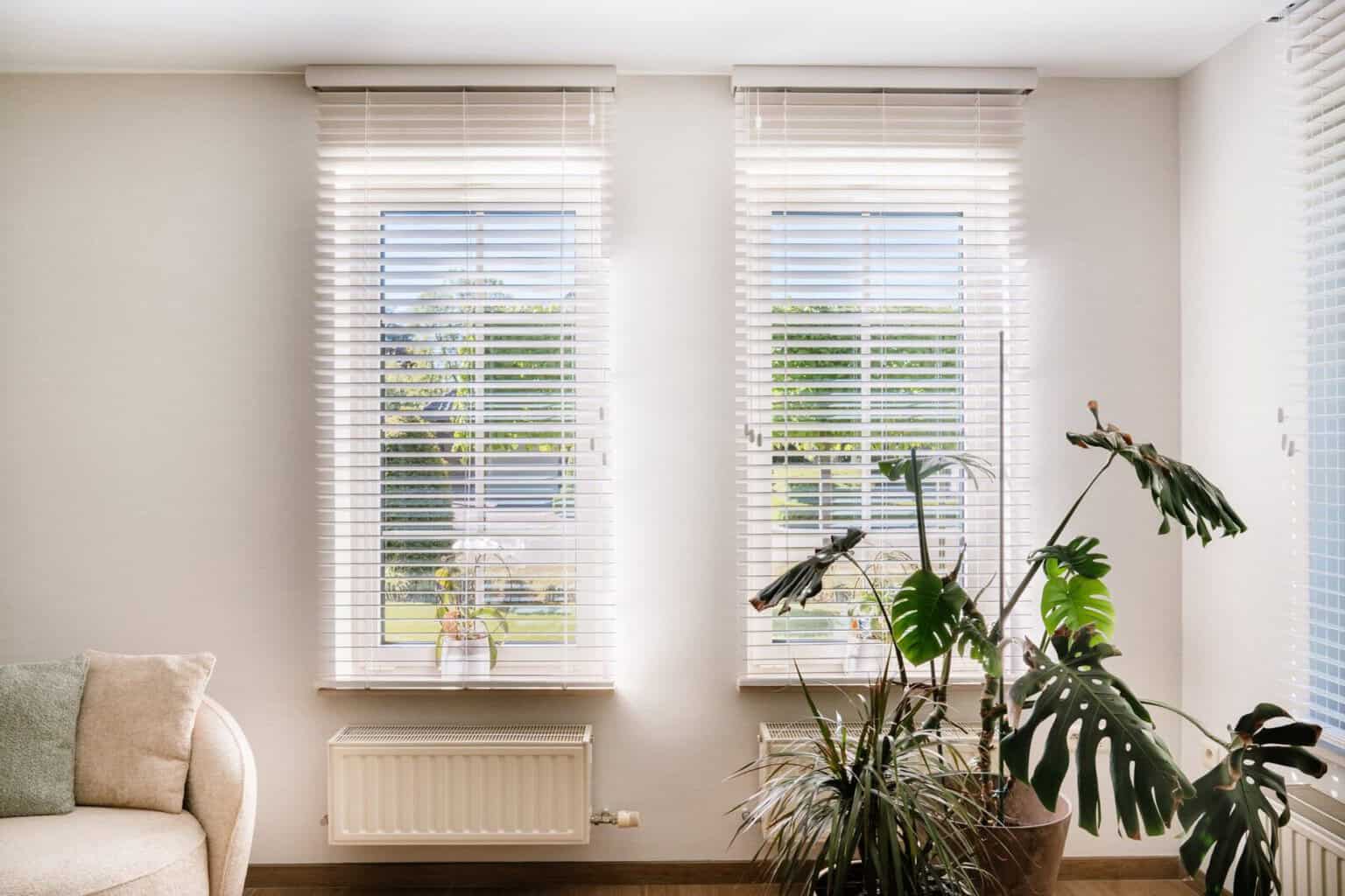 Twee witte houten lamellen naast monstera in hoek van de living — woning Pelt