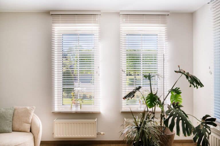 Twee witte houten lamellen naast monstera in hoek van de living — woning Pelt