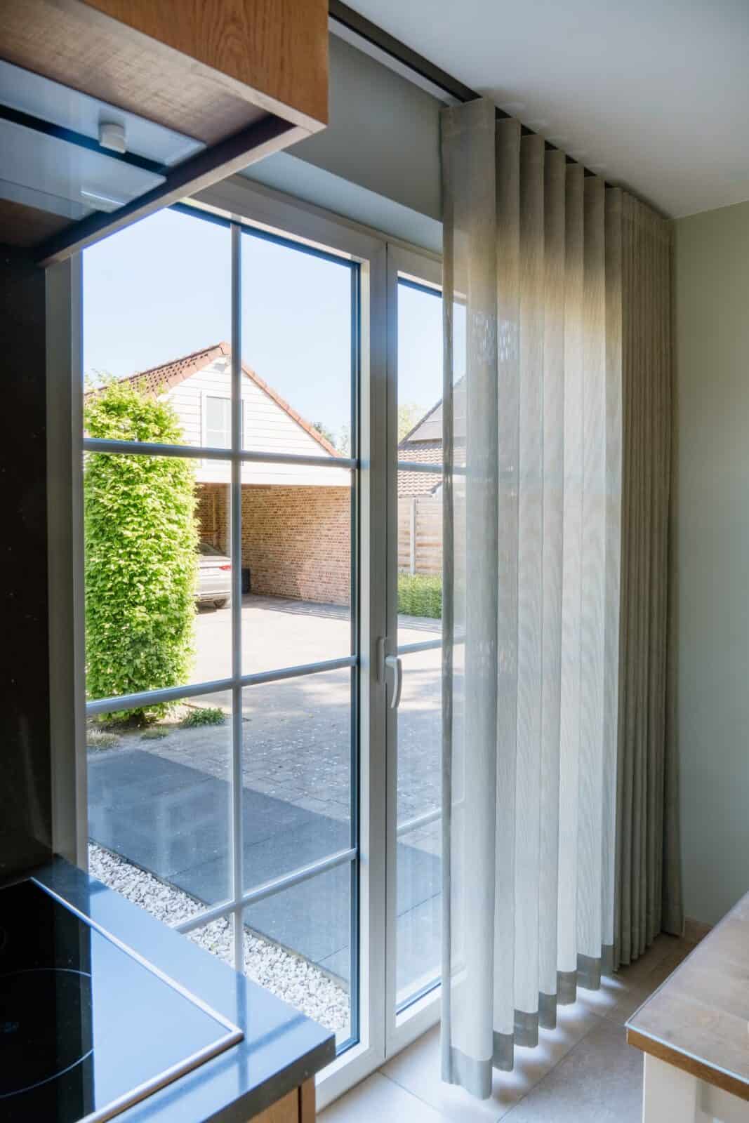Transparant wave gordijn naast glazen deur in keuken — woning Martens Pelt