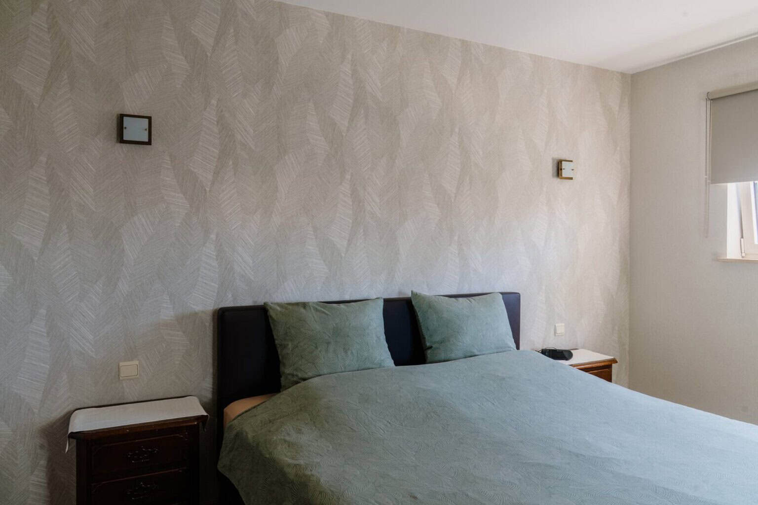 Slaapkamer met botanisch bladerpatroon behang in zachtgrijs — woning Pelt