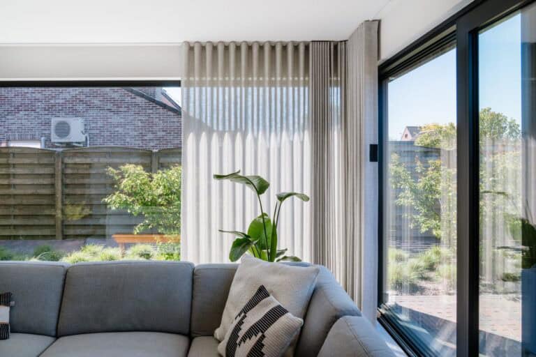Wave gordijnen langs volledige raamwand in hoek van de living — woning Lommel