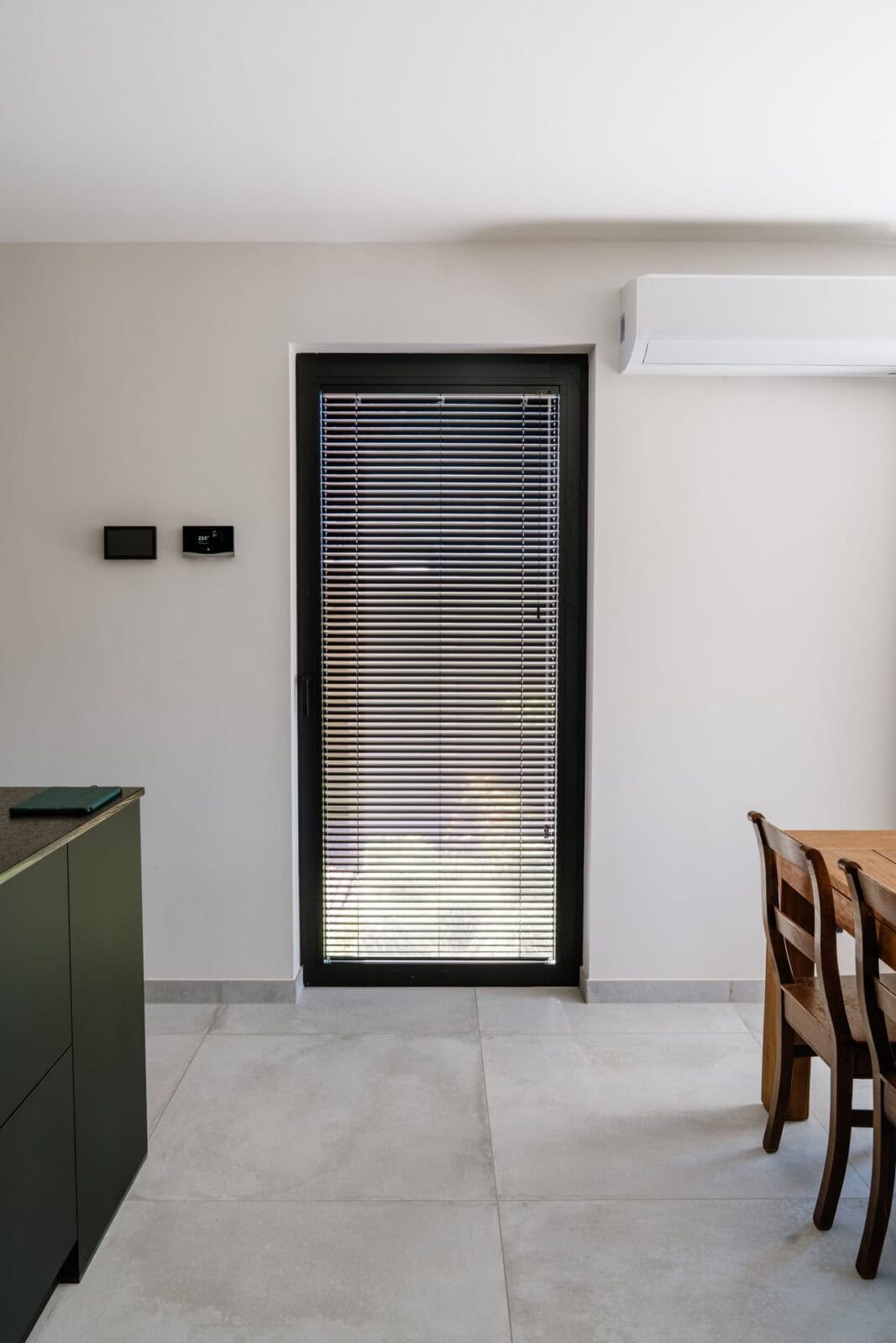 Antraciet aluminium lamellen in smalle deur naast groene keuken — woning Lommel