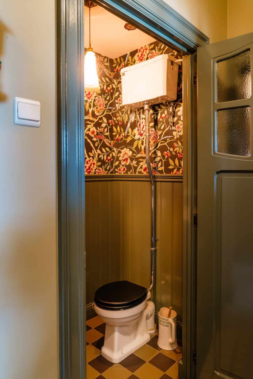 Donker bloemen- en vogelbehang met houten lambrisering in retro toilet — woning Lommel