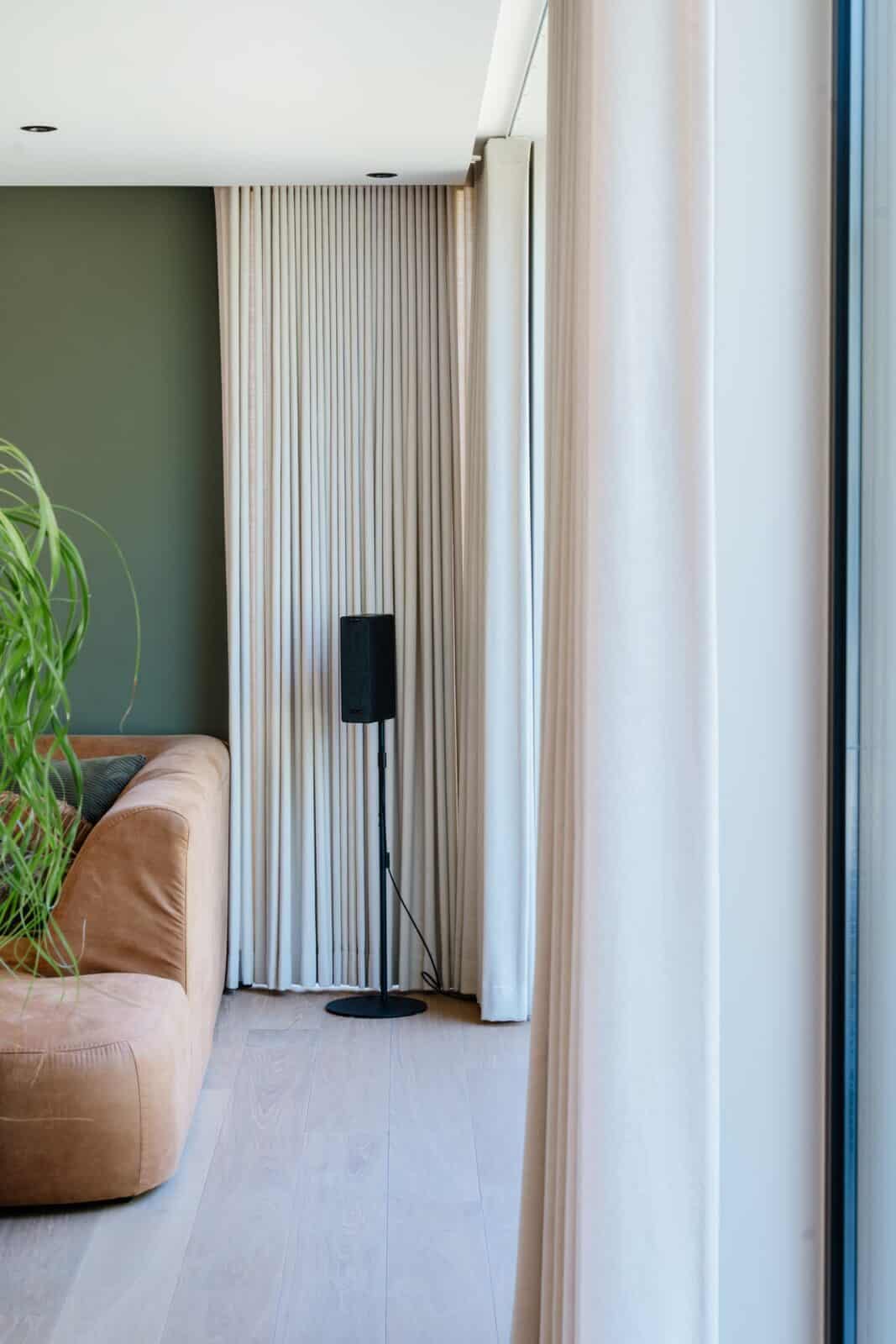 Wave gordijnen in ecru met groene accentmuur en leren sofa - living woning Geel