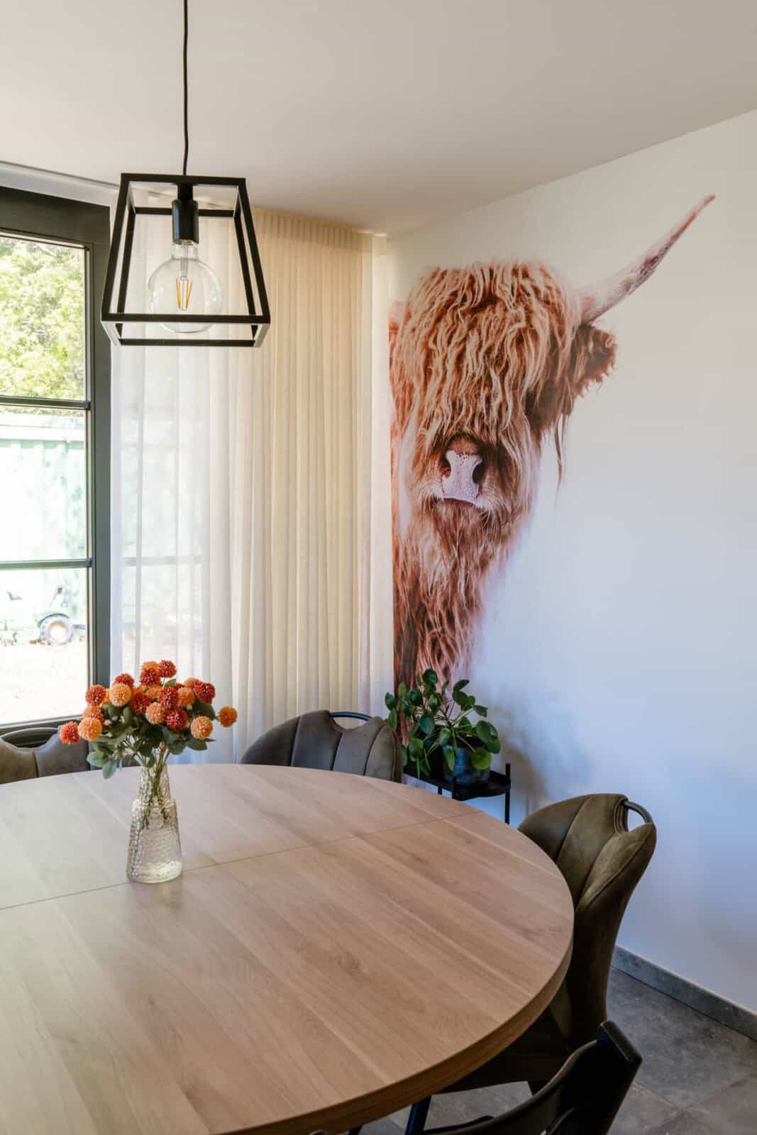 Fotobehang Schotse hooglander op accentmuur naast eethoek met ronde tafel - eetruimte woning Geel