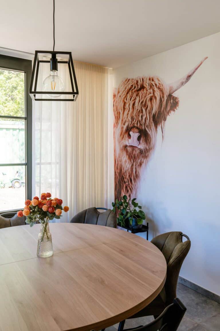 Fotobehang Schotse hooglander op accentmuur naast eethoek met ronde tafel - eetruimte woning Geel