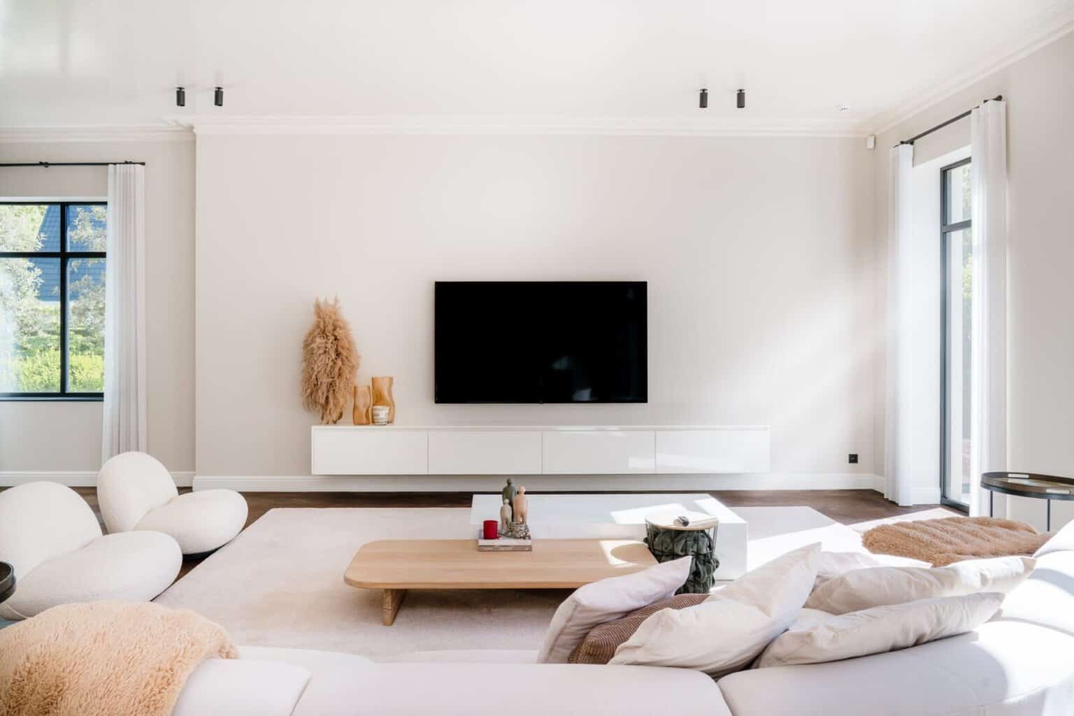 Living met witte gordijnen, lichte wandkleur en sierlijsten langs ramen - living woning Lommel