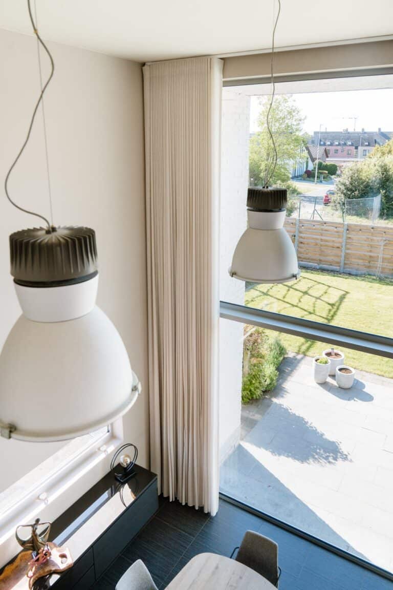 Bovenaanzicht wave gordijn op elektrische rail in vide met industriële hanglampen