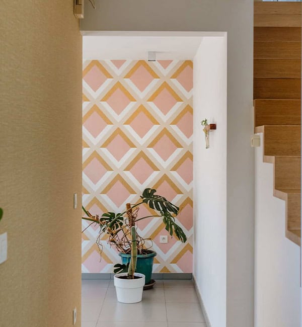 Geometrisch ruitpatroon behang in roze en okergeel in traphal — woning Mol - cropped