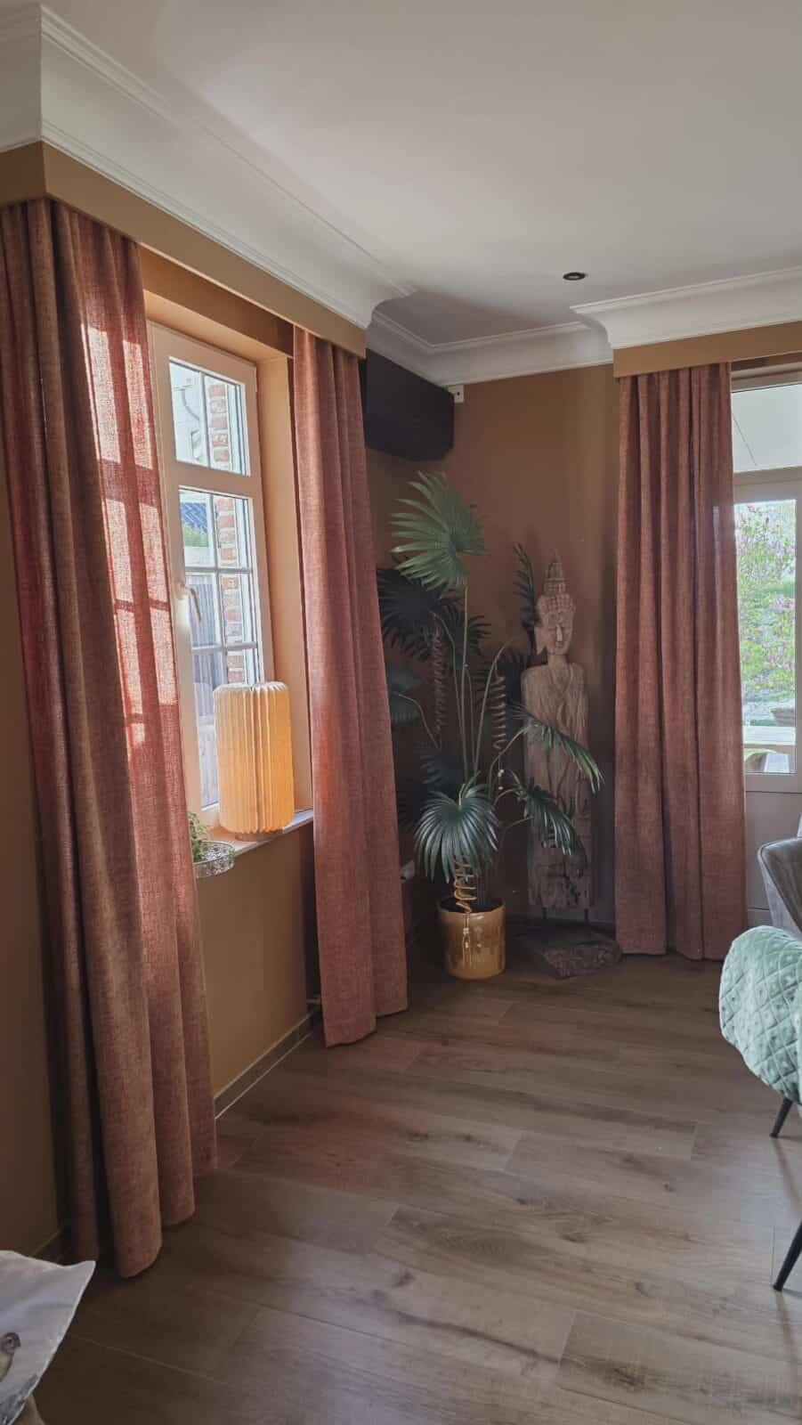 Roestbruine chenille gordijnen in boho woonkamer met sierlijst en Boeddha wanddecoratie – sfeervolle gordijnen van Aerts Interieur Lommel