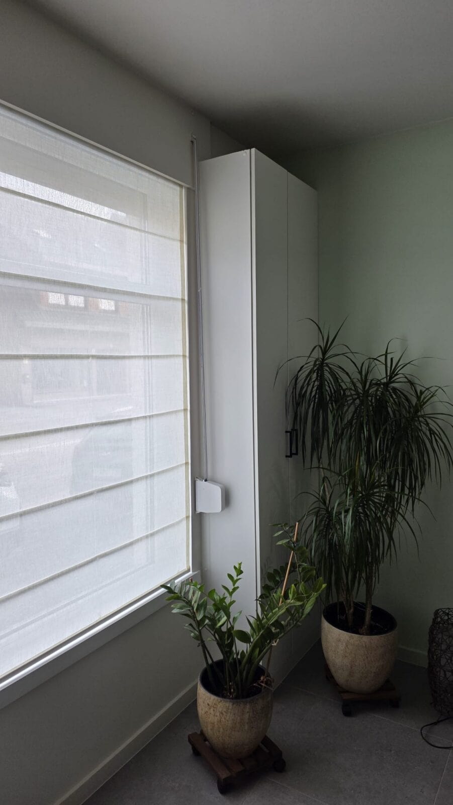 Crèmekleurig vouwgordijn in lichte stof op raam in groene leefruimte met kamerplanten – raamdecoratie van Aerts Interieur Lommel