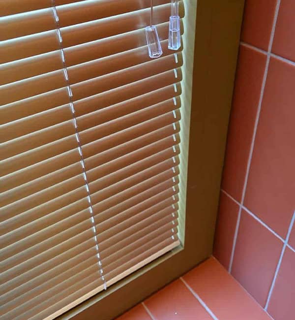 gekleurde alu jaloezieen in badkamer met oranje rode muurtegels